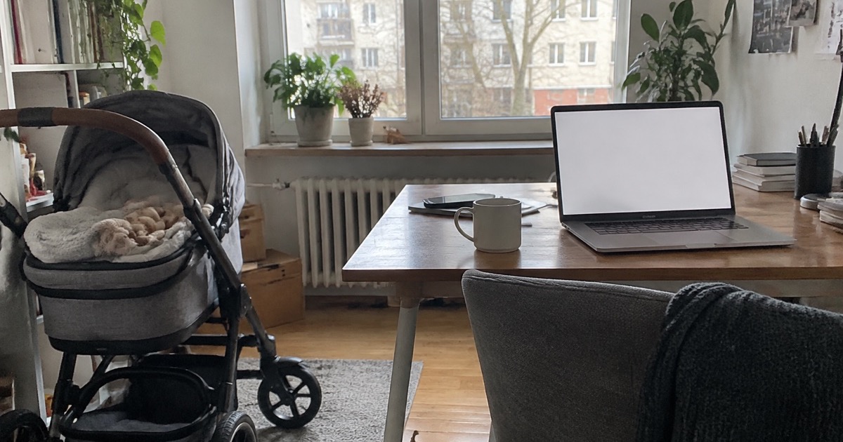 Wózek dziecięcy przy biurku z laptopem w jasnym biurze